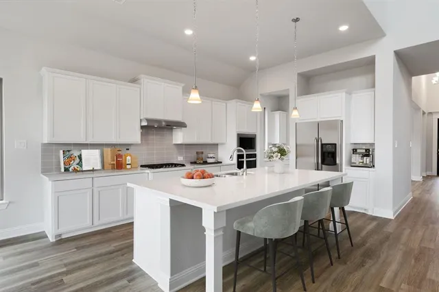 a kitchen with a dining table chairs refrigerator and cabinets