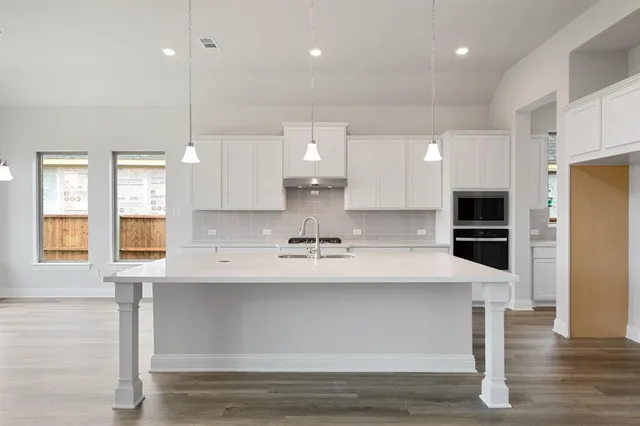 a large kitchen with stainless steel appliances kitchen island a large counter top a stove and a refrigerator