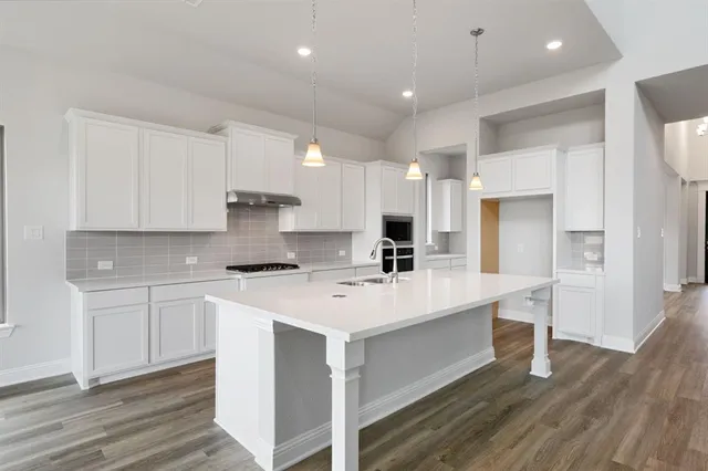 a kitchen with a sink a stove a refrigerator and white cabinets with wooden floor