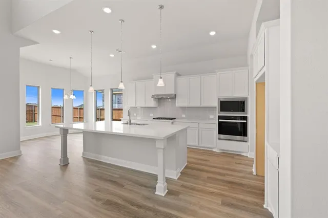 a large white kitchen with lots of counter space a sink appliances and cabinets