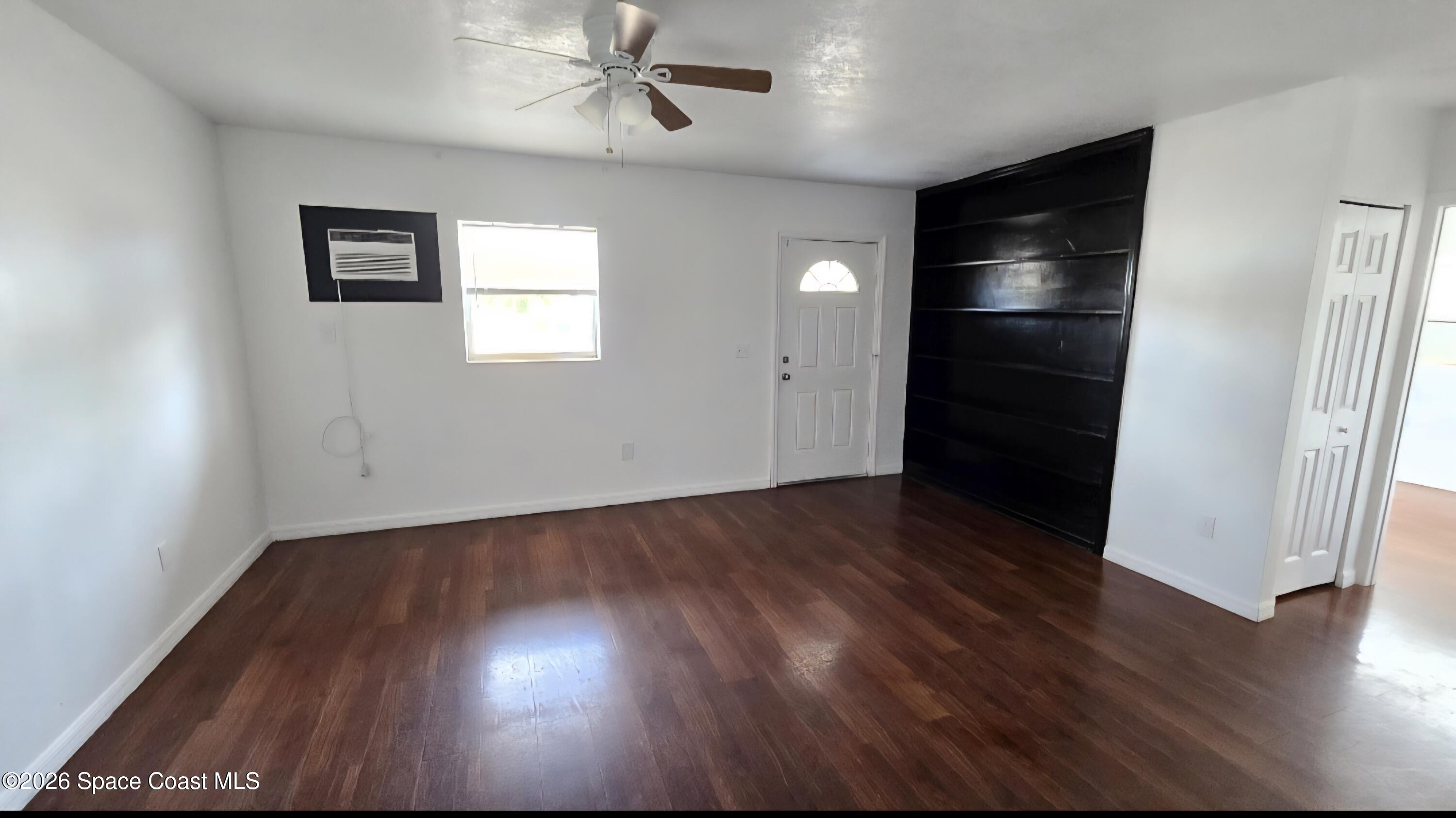 1026 Bacon Circle Northeast, Unit A Palm Bay, FL 32905 - Photo 4 of 12 a view of an empty room with wooden floor and a window