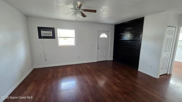 an empty room with wooden floor closet and windows