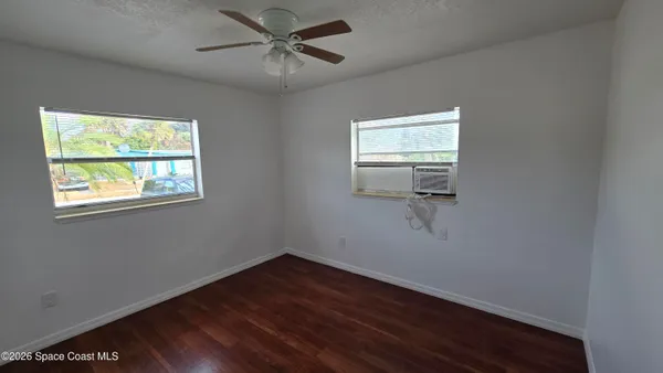 a view of empty room with wooden floor and fan