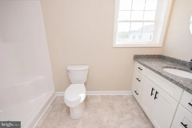 a bathroom with a granite countertop toilet and a sink