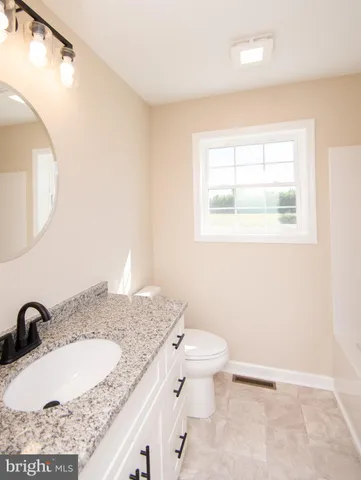 a bathroom with a granite countertop sink a toilet and a mirror