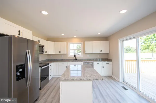 a kitchen with granite countertop a refrigerator stove top oven and sink