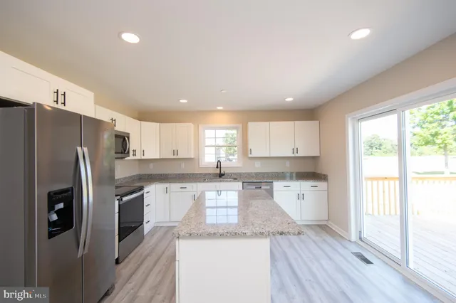 a kitchen with granite countertop a refrigerator stove top oven and sink