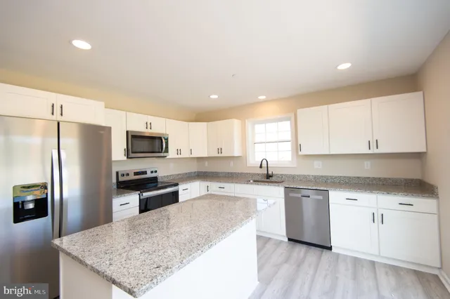 a kitchen with stainless steel appliances granite countertop a sink stove refrigerator and cabinets