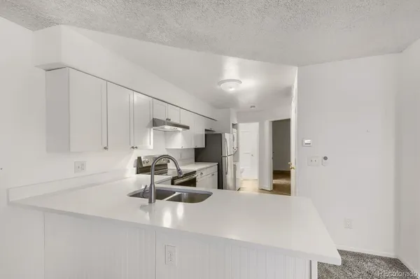 a kitchen with stainless steel appliances a refrigerator sink and white cabinets