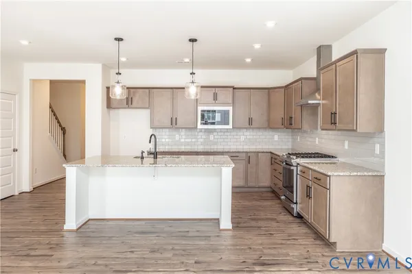 a large kitchen with stainless steel appliances kitchen island granite countertop a sink stove and refrigerator