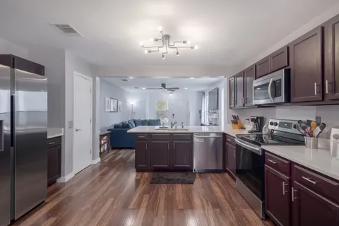 a kitchen with stainless steel appliances granite countertop a stove a sink dishwasher and a microwave oven on the wooden floor