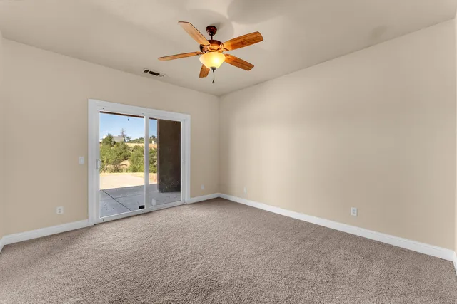 an empty room with ceiling fan and window