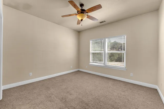 an empty room with windows and fan
