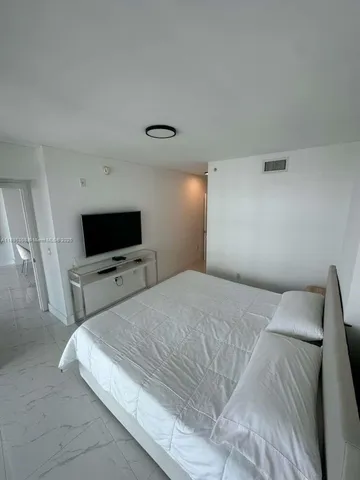 a bedroom with a bed and a flat screen tv