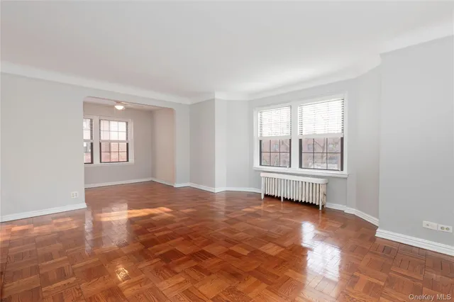 a view of an empty room with window and wooden floor