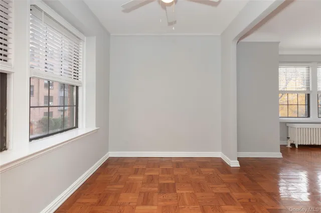 an empty room with windows and chandelier fan