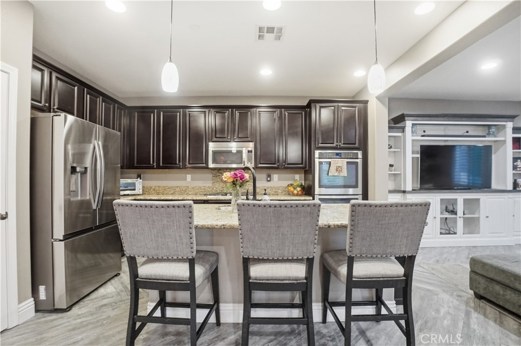 25654 Red Hawk Road Corona, CA 92883 - Photo 11 of 75 a kitchen with stainless steel appliances granite countertop a dining table chairs refrigerator and microwave