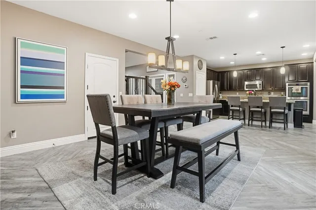 a kitchen with stainless steel appliances granite countertop a dining table chairs refrigerator and microwave