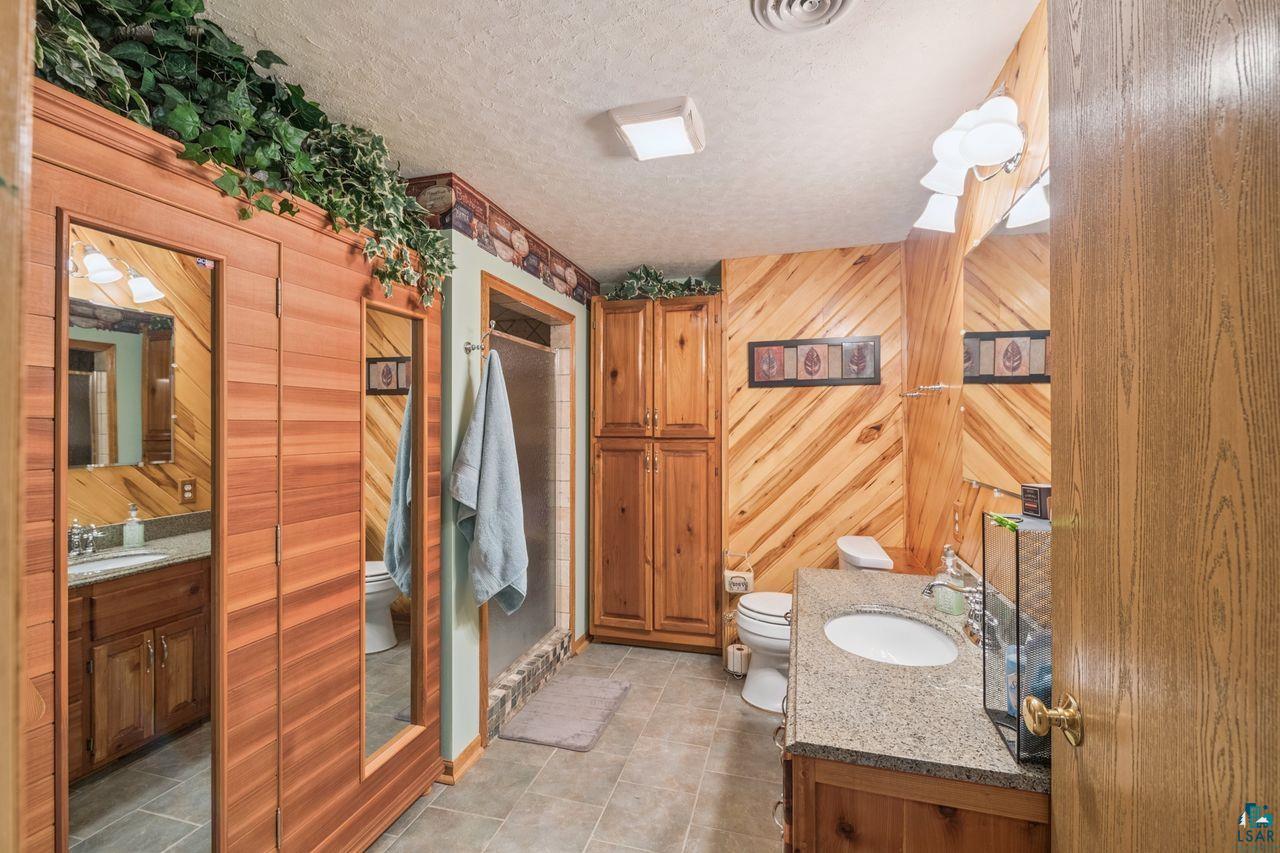 48424 Beaser Road Ashland, WI 54806 - Photo 11 of 30 Full bath featuring vanity, wood walls, and a textured ceiling
