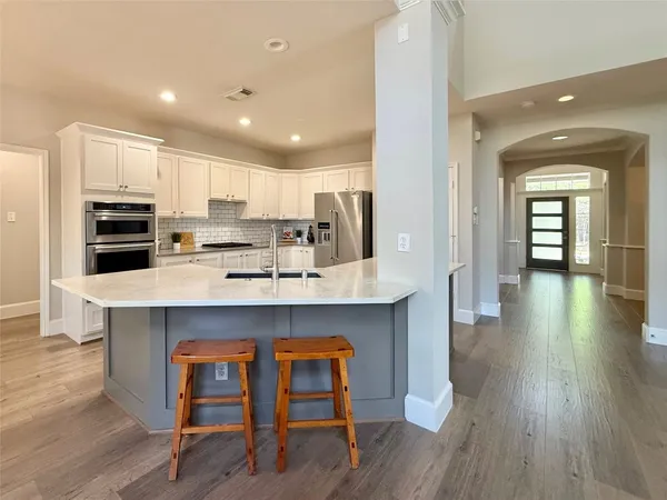 a kitchen with stainless steel appliances a kitchen island hardwood floor sink stove and wooden cabinets
