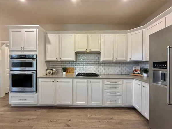a kitchen with stainless steel appliances granite countertop a stove and white cabinets