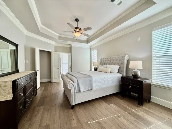 a bedroom with a bed a dresser and wooden floor