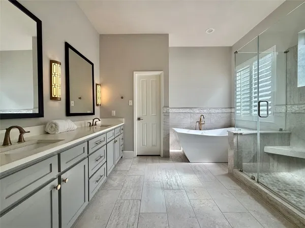 a bathroom with a double vanity sink mirror and bathtub