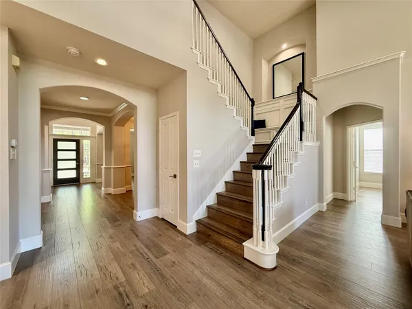 a view of a hallway with wooden floor staircase and a living room