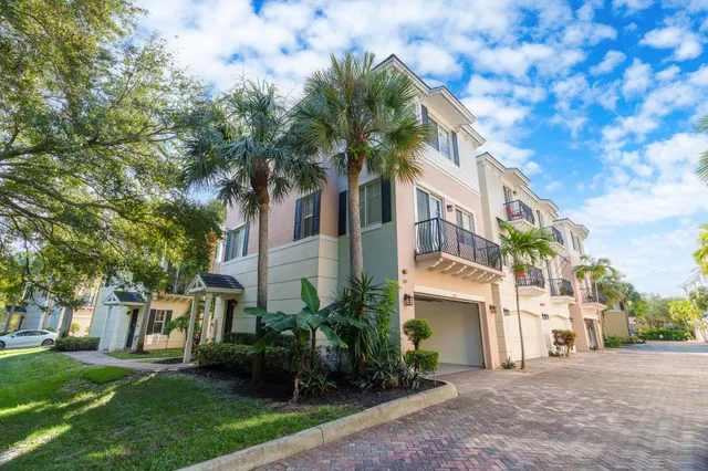 a view of a white house next to a yard with palm trees