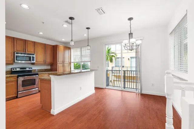 a kitchen with stainless steel appliances granite countertop hardwood floor sink stove and wooden cabinets