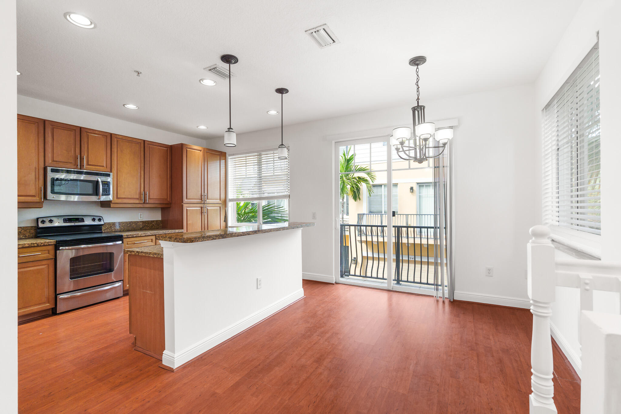 3830 Northwest 5th Terrace Boca Raton, FL 33431 - Photo 10 of 34 a kitchen with stainless steel appliances granite countertop hardwood floor sink stove and wooden cabinets