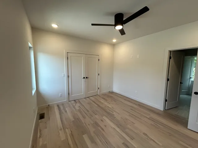 an empty room with wooden floor cabinet and a ceiling fan