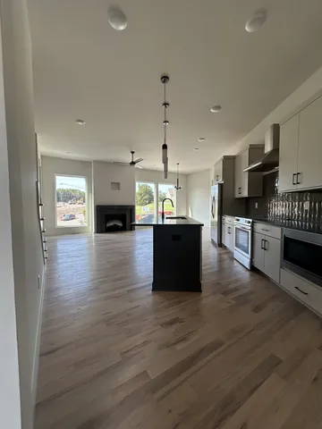 a large kitchen with stainless steel appliances granite countertop a stove top oven a sink dishwasher and a fireplace with wooden floor