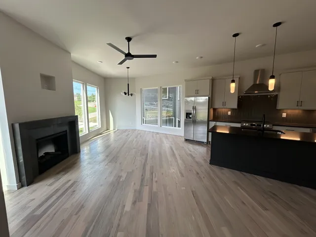 a big room with chandelier kitchen view and a wooden floor