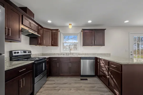 a kitchen with stainless steel appliances granite countertop wooden cabinets a sink a stove and a refrigerator