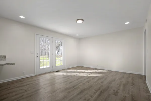 an empty room with wooden floor and windows