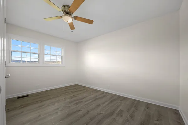 an empty room with a window and a ceiling fan