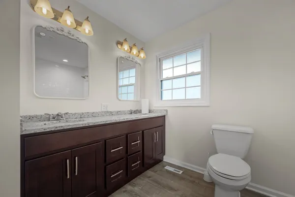 a bathroom with a granite countertop toilet a sink and a mirror