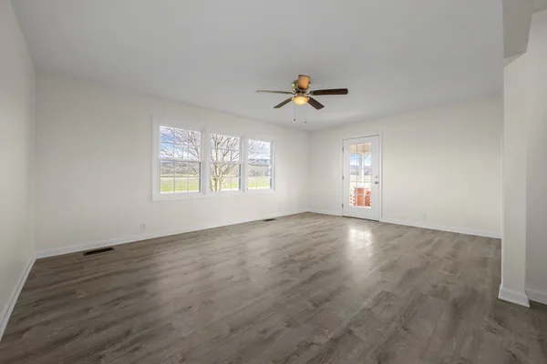 a view of an empty room with a window and wooden floor