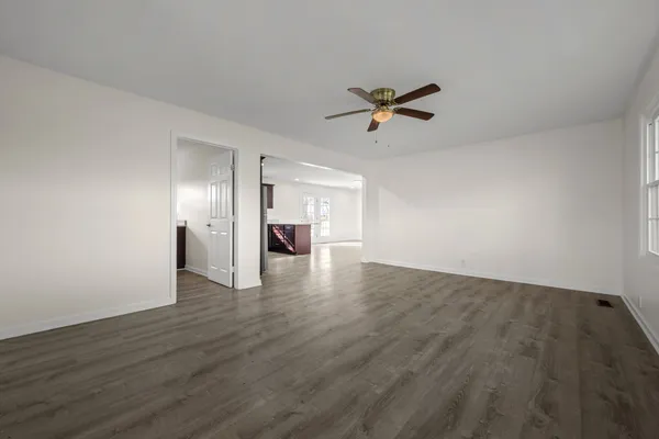a view of empty room with wooden floor and ceiling fan