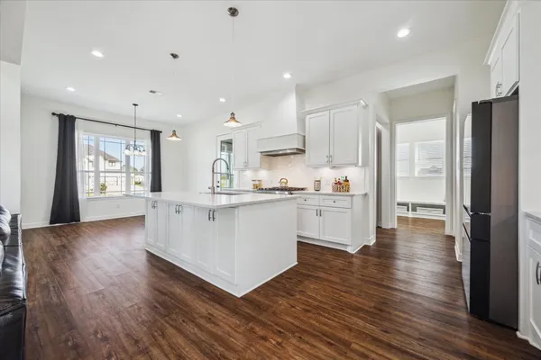 a kitchen with white cabinets and wooden floor