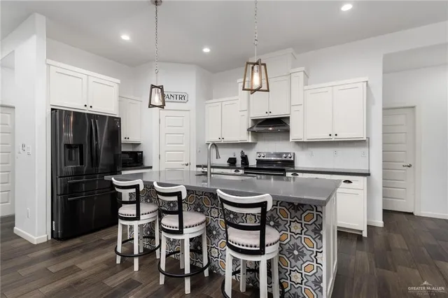 a kitchen with stainless steel appliances a dining table chairs refrigerator and microwave
