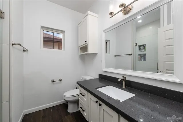 a bathroom with a granite countertop sink a toilet and a mirror