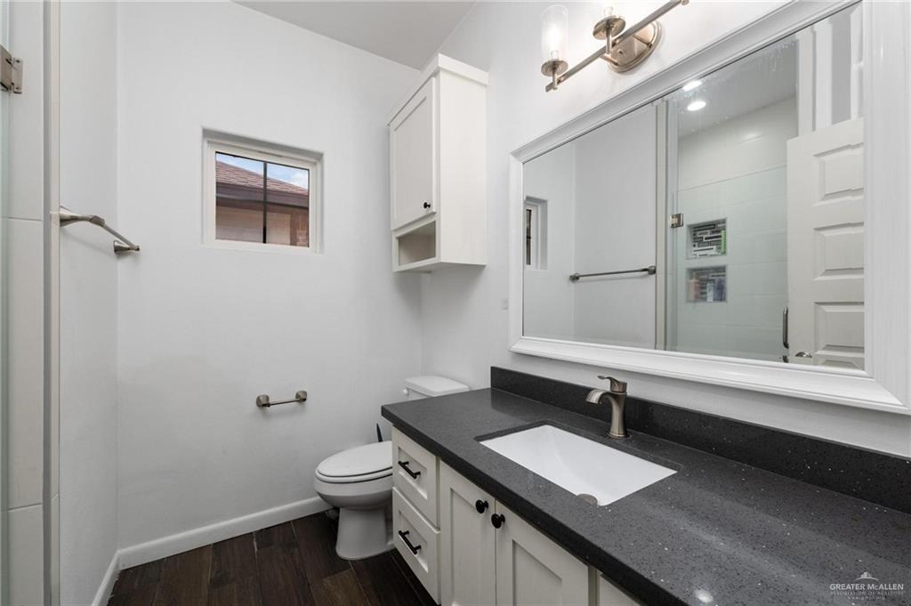 405 Scarlett Red Harlingen, TX 78552 - Photo 6 of 15 a bathroom with a granite countertop sink a toilet and a mirror