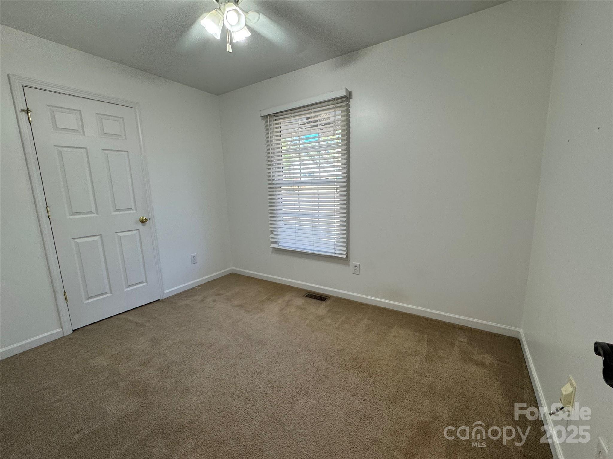 314 East Louisiana Avenue Bessemer City, NC 28016 - Photo 8 of 15 an empty room with a chandelier fan and windows