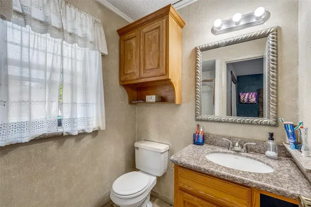 a bathroom with a granite countertop sink a mirror and a toilet