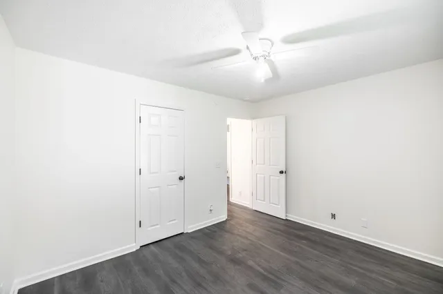 an empty room with wooden floor and fan