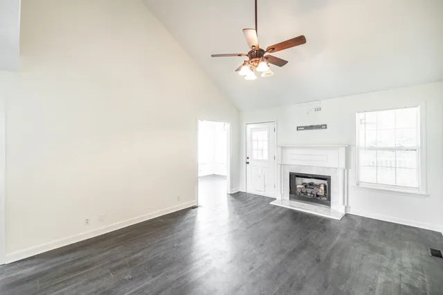 an empty room with wooden floor fireplace and windows