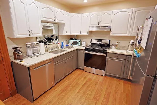 a kitchen with granite countertop a sink cabinets and stainless steel appliances