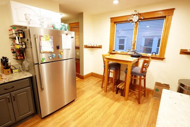 a kitchen with stainless steel appliances granite countertop a refrigerator a stove and a dining table with wooden floor